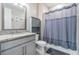 Cozy bathroom with a granite vanity top, grey cabinets, matching cabinet and combination shower and tub at 4849 Isola Ct, Wesley Chapel, FL 33543