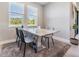 Modern dining room with a marble top table set on a soft gray rug and a view of lush, green trees outside at 4849 Isola Ct, Wesley Chapel, FL 33543