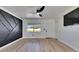 Bright living room featuring light wood floors, a black accent wall and a ceiling fan at 564 Florida S Cir, Apollo Beach, FL 33572