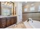 Luxurious primary bathroom features a double vanity, soaking tub, and walk-in shower with neutral tiling at 5914 Fitzgerald Rd, Odessa, FL 33556