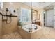 Beautiful bathroom featuring a large soaking tub, neutral tile, and frameless shower with a rain shower head at 5914 Fitzgerald Rd, Odessa, FL 33556