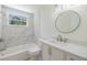 Updated bathroom features a shower-tub, white marble tile, and modern vanity with a round mirror at 6214 Westport Dr, Port Richey, FL 34668