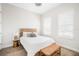 Bright bedroom featuring a bed with white linens, wood floors, windows with shutters, and a decorative bench at 7122 Bowspirit Pl, Apollo Beach, FL 33572