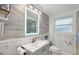 Bright bathroom featuring a modern vanity, decorative mirror, and stylish hexagonal and wood-look tile accents at 7740 Bracken Dr, Port Richey, FL 34668