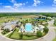 Aerial view of a community pool and splash pad with landscaping, surrounded by sports courts and green spaces at 8721 Savory Walk Dr, Land O Lakes, FL 34637