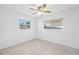 Bedroom with terrazzo floors, ceiling fan, and natural light streaming in from two windows at 9017 Petal Ct, Hudson, FL 34667