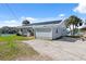A charming home with solar panels, gravel driveway, and mature palm trees at 9017 Petal Ct, Hudson, FL 34667