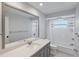 Well-lit bathroom with gray vanity, white countertops, large mirror, and shower-tub combo at 902 Marco Ne Dr, St Petersburg, FL 33702