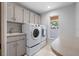 Bright laundry room featuring front-load washer and dryer, ample cabinetry, a utility sink and window at 902 Marco Ne Dr, St Petersburg, FL 33702