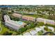 Aerial view of a residential complex featuring a pool, lush greenery, water views and community amenities at 9433 Harbor Greens Way # 405, Seminole, FL 33776