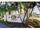 Entrance sign for Harbor Greens, a private residential community, framed by mature palm trees and colorful plants at 9433 Harbor Greens Way # 405, Seminole, FL 33776