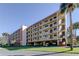 Spacious condo building featuring multiple balconies, covered parking, and lush landscaping at 9433 Harbor Greens Way # 405, Seminole, FL 33776