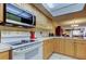 Kitchen with microwave, white range, neutral countertops, and light wood cabinetry, view into dining area at 9433 Harbor Greens Way # 405, Seminole, FL 33776