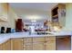 Kitchen showing stainless steel dishwasher, light wood cabinetry, and neutral countertops and view into dining area at 9433 Harbor Greens Way # 405, Seminole, FL 33776