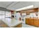 Meeting room kitchenette with white appliances, wood cabinets, and a convenient island for meal prep at 9433 Harbor Greens Way # 405, Seminole, FL 33776