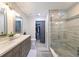Bright bathroom featuring a double vanity, glass-enclosed shower, and a closet with a grey curtain at 9730 Lake Chase Island Way # 9730, Tampa, FL 33626
