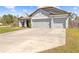 Angle of the front exterior featuring a three-car garage, muted gray exterior and well kept lawn at 11092 Jenny Wren Rd, Weeki Wachee, FL 34614