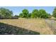 Expansive backyard with a chain-link fence, bordered by trees and a glimpse of a pond at 1225 Harvest Home Ct, Ruskin, FL 33570