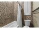 Stylish bathroom features mosaic tiled walls, a tub, a toilet and a window with charming plantation shutters at 13206 Lewis Raulerson Road, Dover, FL 33527