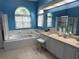Bright bathroom featuring large windows, a soaking tub, a separate glassed in shower, and a double vanity at 2069 Overbrook Ln, Spring Hill, FL 34606