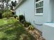 Exterior house detail showing manicured landscaping, a hose spigot, and healthy green grass at 2069 Overbrook Ln, Spring Hill, FL 34606