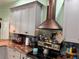 Modern kitchen with gray cabinetry, stainless steel appliances, decorative range hood, and granite countertops at 2069 Overbrook Ln, Spring Hill, FL 34606