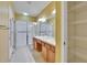 Well-lit bathroom featuring double sinks, a spacious shower with sliding glass doors, and convenient storage shelving at 2128 River Turia Cir # 2128, Riverview, FL 33578