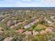 Wide aerial view showcasing a house with a screened pool, surrounded by lush landscaping and a neighborhood at 2136 Pinnacle N Cir, Palm Harbor, FL 34684