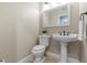A well-lit half bath features a pedestal sink, toilet, mirror, and towel rack at 2136 Pinnacle N Cir, Palm Harbor, FL 34684
