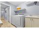 Functional laundry room with modern washer, dryer, sink, and storage shelves at 2136 Pinnacle N Cir, Palm Harbor, FL 34684