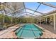 Outdoor pool and spa surrounded by lush landscaping, screened enclosure, and a brick patio at 2136 Pinnacle N Cir, Palm Harbor, FL 34684