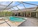 Outdoor pool and spa with a screened enclosure, brick patio, under a bright blue sky at 2136 Pinnacle N Cir, Palm Harbor, FL 34684