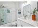 Bright bathroom featuring a glass-enclosed shower, white cabinets, white quartz countertops and a stylish mirror at 311 Poinsettia Rd, Anna Maria, FL 34216