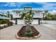 Inviting two-story coastal home with dual garages, balcony, stone accents, palm trees, and a well-kept lawn at 311 Poinsettia Rd, Anna Maria, FL 34216