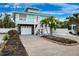 Stunning two-story coastal home with single garage, stairs to the balcony, stone accents, palm trees, and brick-lined flower bed at 311 Poinsettia Rd, Anna Maria, FL 34216