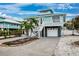 Beautiful two-story coastal home with single garage, stairs to the balcony, stone accents, and palm trees at 311 Poinsettia Rd, Anna Maria, FL 34216