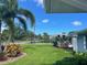 Landscaped front yard features lush green grass, mature trees, and well-manicured shrubs at 560 Baywood N Dr, Dunedin, FL 34698