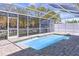 A gorgeous screened-in pool with brick patio, surrounded by a white frame at 560 Baywood N Dr, Dunedin, FL 34698