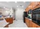 Well lit kitchen features tile floors, wood cabinets and modern black appliances at 6327 Sunset Bay Cir, Apollo Beach, FL 33572