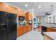 Open kitchen with black appliances, wood cabinets, and adjacent living area at 6327 Sunset Bay Cir, Apollo Beach, FL 33572