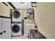 Compact laundry room with stacked washer and dryer, plus a utility sink at 6395 Pinestand Ct, Spring Hill, FL 34606