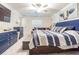 Well-lit bedroom with a blue bed, ceiling fan, carpet, and a sofa visible in the background at 6494 Beverly Hills Dr, Zephyrhills, FL 33541