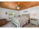 Cozy bedroom featuring a wood-paneled ceiling, ceiling fan, and a comfortable bed with floral bedding at 6606 Dolphin Cove Dr, Apollo Beach, FL 33572