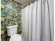 Tastefully decorated bathroom showcasing tropical-themed wallpaper, a toilet, and a shower with a neutral-colored curtain at 1655 S Highland Ave # G164, Clearwater, FL 33756