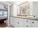 Bathroom vanity area boasts white cabinets, a stone countertop, and a large mirror with Hollywood lighting at 16573 Hutchison Rd, Odessa, FL 33556