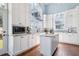 Bright kitchen features white cabinets, island, granite counters, stainless appliances, and hardwood floors at 16573 Hutchison Rd, Odessa, FL 33556