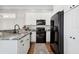 Well-appointed kitchen with white cabinetry, black appliances, granite countertops, and hardwood floors at 16573 Hutchison Rd, Odessa, FL 33556