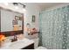 Cozy bathroom with a wood-framed mirror, a flower-patterned shower curtain and wood shelves at 1904 Canterbury Ln # 21, Sun City Center, FL 33573