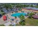 Aerial view of a community pool with plenty of seating, palm trees, and a spacious parking area nearby at 206 Glenellen Pl, Sun City Center, FL 33573