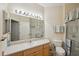Well-lit bathroom featuring a large mirror, single sink, shower, and toilet with grab bars at 2129 Acadia Greens Dr, Sun City Center, FL 33573
